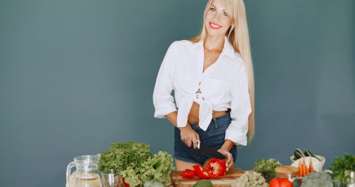 A smiling blonde woman chops vegetables, promoting healthy eating and lifestyle.
